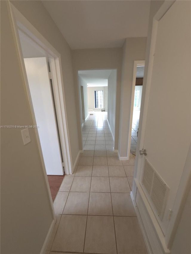 hall with light tile patterned floors, baseboards, and visible vents