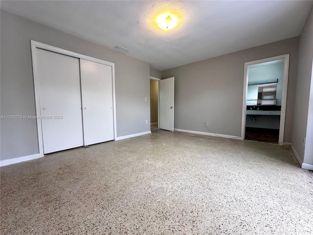 unfurnished bedroom with speckled floor, a closet, visible vents, and baseboards