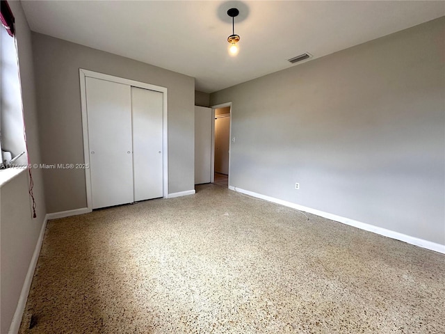 unfurnished bedroom with a closet, visible vents, baseboards, and speckled floor