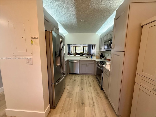 kitchen featuring electric panel, stainless steel appliances, light countertops, light wood-style floors, and a sink