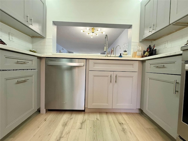 kitchen with light wood-type flooring, gray cabinets, light countertops, and dishwasher