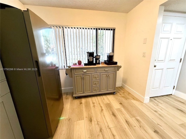 interior space with light wood finished floors, baseboards, and a textured ceiling