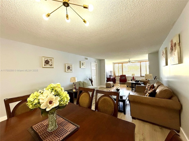 dining space with visible vents, baseboards, a textured ceiling, and light wood finished floors