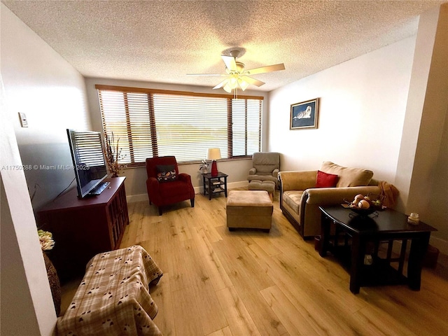 living area with ceiling fan, light wood finished floors, a textured ceiling, and baseboards