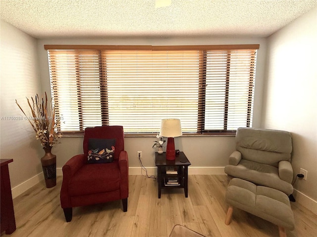 sitting room featuring light wood finished floors, baseboards, and a wealth of natural light