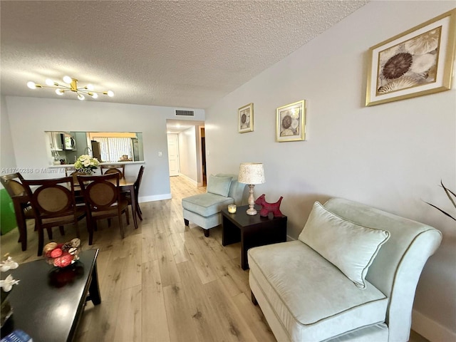 living area featuring light wood-style flooring, visible vents, and a textured ceiling