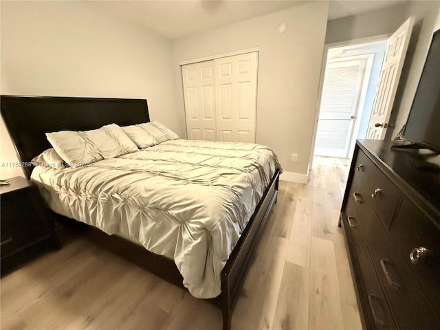 bedroom featuring light wood-style floors, baseboards, and a closet