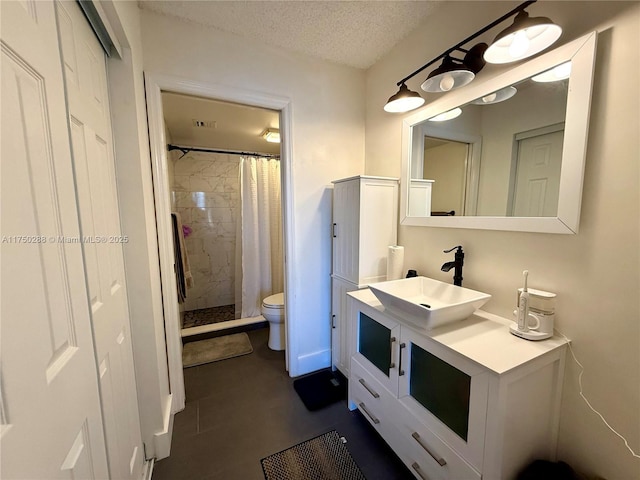 bathroom with a textured ceiling, toilet, vanity, visible vents, and a shower stall