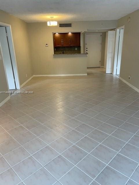 unfurnished living room featuring light tile patterned floors, visible vents, and baseboards