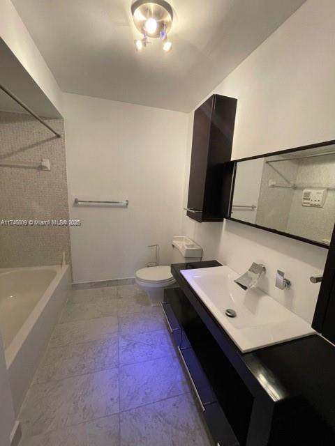 bathroom with toilet, bathtub / shower combination, baseboards, and vanity
