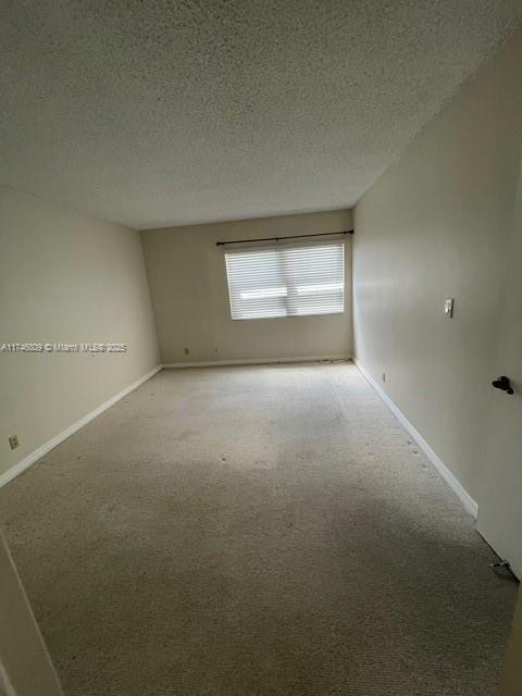 carpeted empty room with baseboards and a textured ceiling