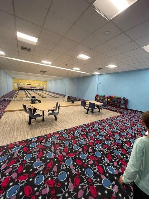 playroom with a paneled ceiling, a bowling alley, visible vents, and wood finished floors