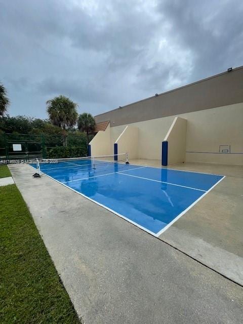 exterior space with a tennis court and fence