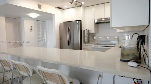 kitchen with under cabinet range hood, white cabinetry, electric stove, freestanding refrigerator, and modern cabinets