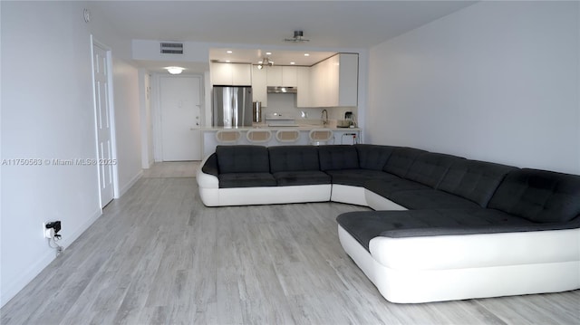 living area featuring light wood finished floors, visible vents, and baseboards