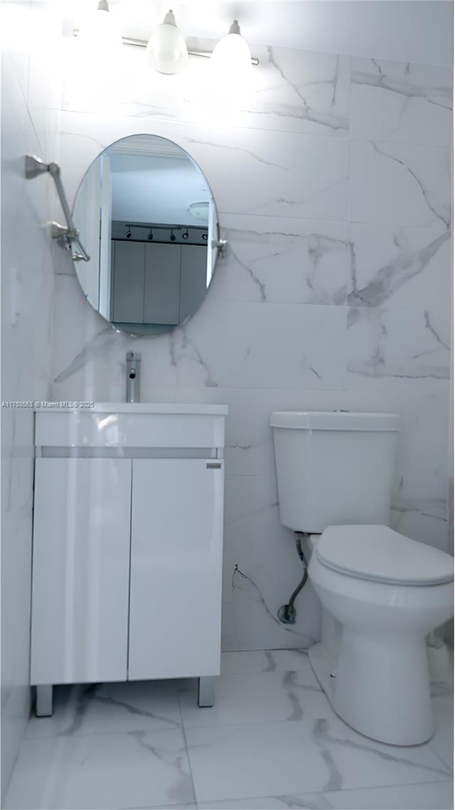 bathroom featuring toilet, marble finish floor, and vanity