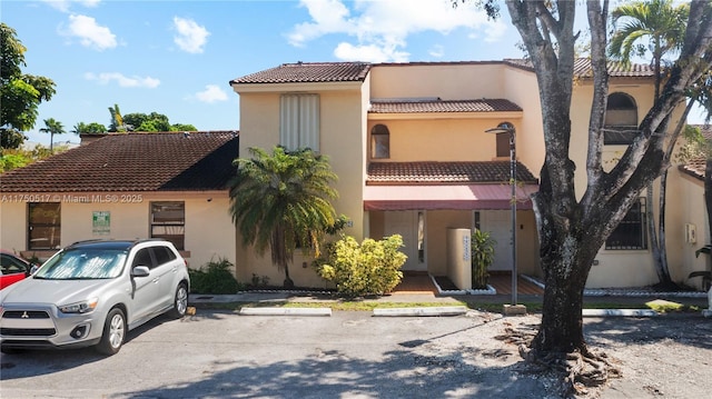 exterior space featuring uncovered parking, a tiled roof, and stucco siding