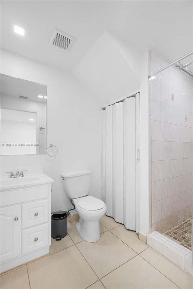 full bath featuring toilet, vanity, visible vents, tiled shower, and tile patterned floors