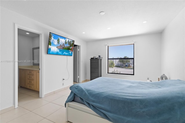 bedroom featuring light tile patterned floors, a textured ceiling, baseboards, and connected bathroom