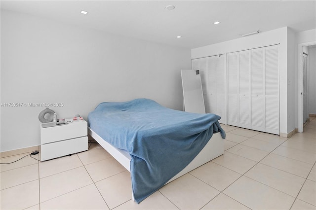 tiled bedroom featuring baseboards, multiple closets, and recessed lighting