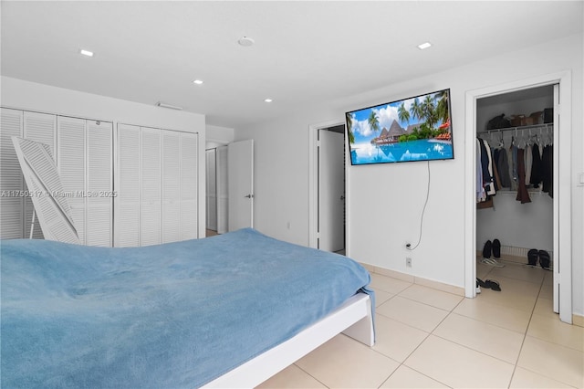 bedroom with light tile patterned floors, baseboards, a walk in closet, and recessed lighting