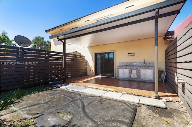 exterior space featuring a patio area, fence, and stucco siding