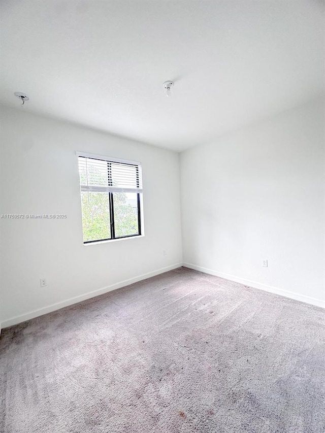 carpeted empty room with baseboards