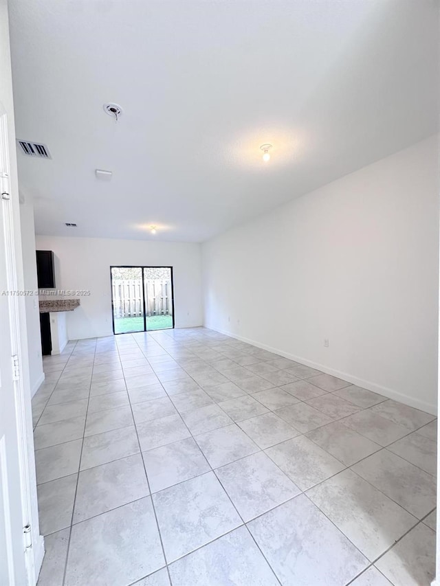 empty room with light tile patterned floors, visible vents, and baseboards