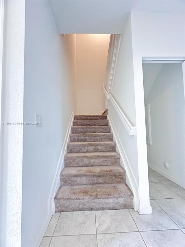 stairway featuring tile patterned flooring and baseboards