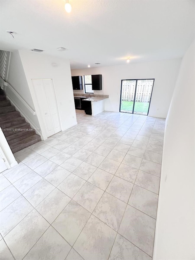 unfurnished living room featuring visible vents, stairway, and light tile patterned flooring