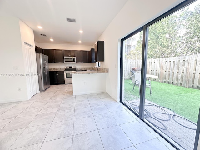 kitchen featuring light tile patterned floors, appliances with stainless steel finishes, visible vents, and light stone countertops