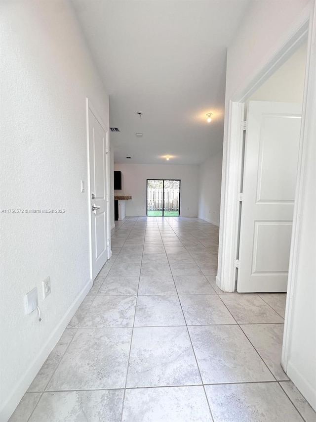 hall featuring baseboards and light tile patterned flooring