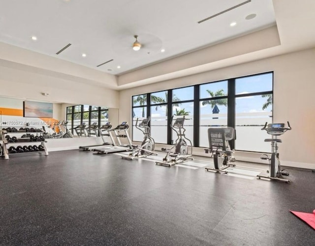 exercise room featuring recessed lighting, a raised ceiling, ceiling fan, and baseboards