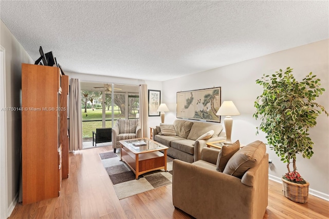 living room featuring a textured ceiling, baseboards, and light wood-style floors