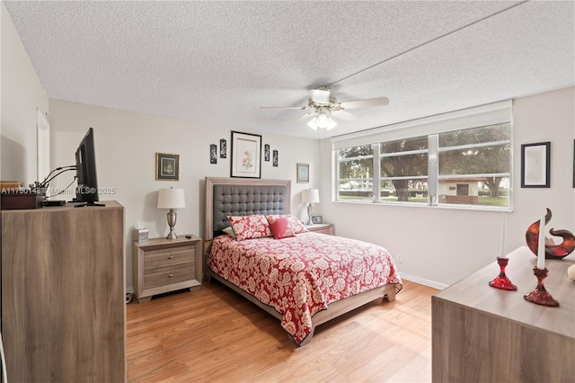 bedroom featuring a ceiling fan, a textured ceiling, baseboards, and wood finished floors