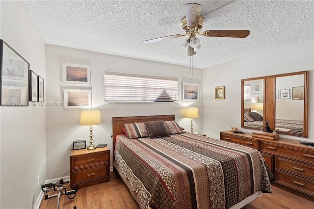 bedroom with a textured ceiling, ceiling fan, light wood finished floors, and baseboards