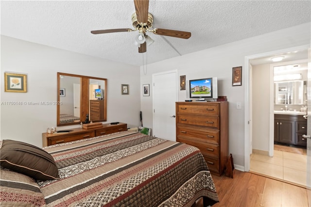 bedroom with a ceiling fan, light wood-style flooring, a textured ceiling, and ensuite bathroom