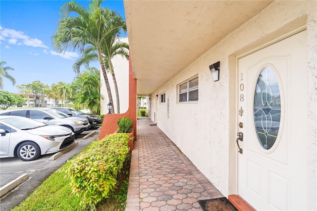 doorway to property featuring uncovered parking and stucco siding