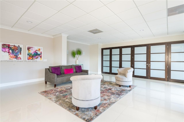 living area with a paneled ceiling, light tile patterned flooring, crown molding, and baseboards