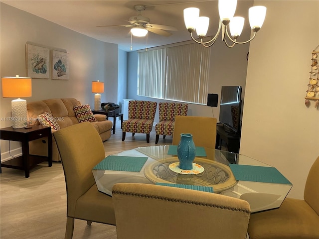 dining space featuring light wood-type flooring and ceiling fan with notable chandelier