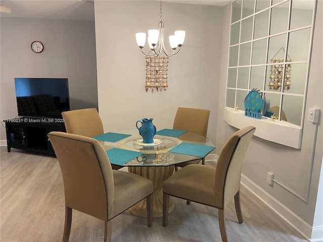 dining room featuring baseboards, wood finished floors, and an inviting chandelier