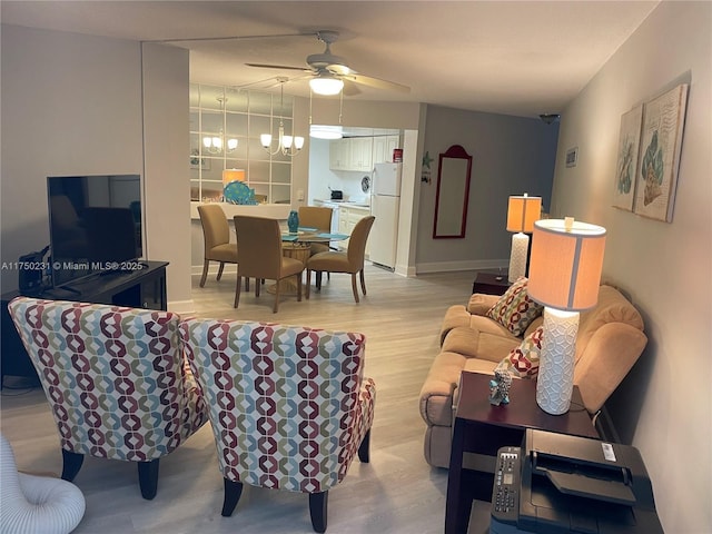 living area with light wood-style flooring, baseboards, and ceiling fan with notable chandelier