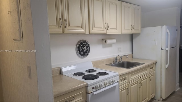 kitchen featuring white appliances, light countertops, a sink, and cream cabinetry