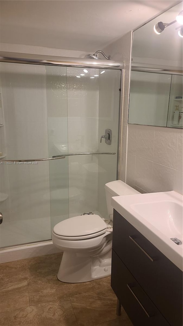 full bathroom with toilet, vanity, tile walls, decorative backsplash, and a stall shower