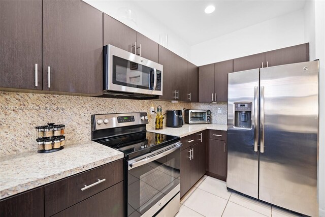 kitchen with tasteful backsplash, dark brown cabinetry, light tile patterned floors, and stainless steel appliances