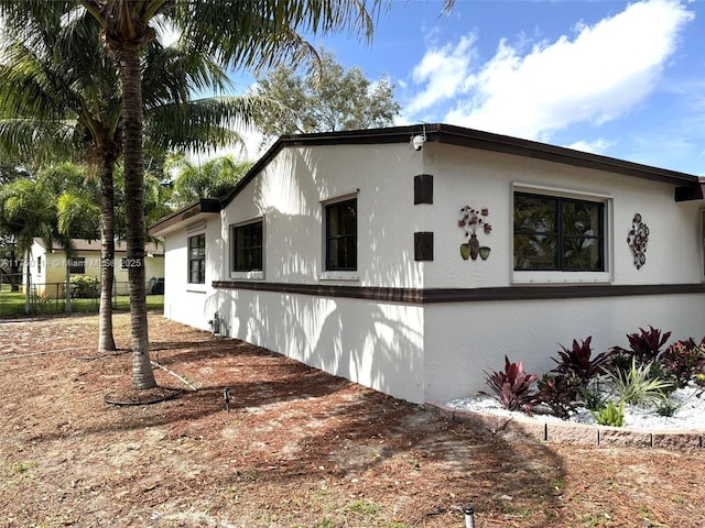 view of side of property with fence and stucco siding