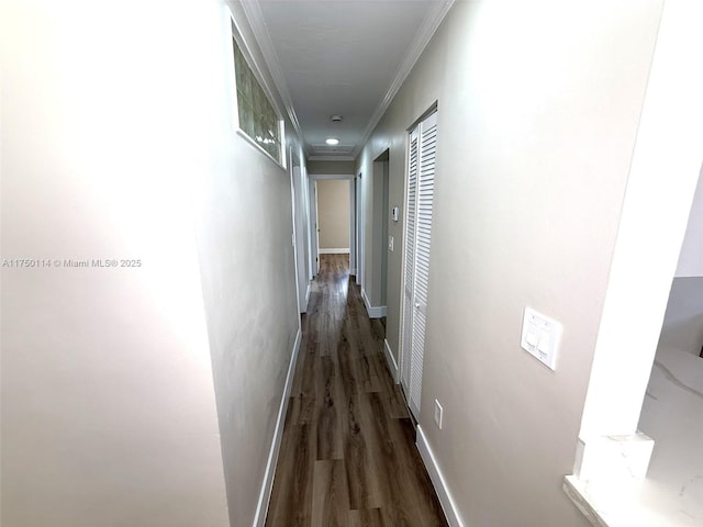 hall with dark wood-style floors, ornamental molding, and baseboards