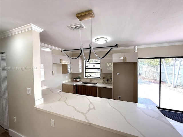 kitchen featuring visible vents, a sink, white cabinetry, and light stone countertops