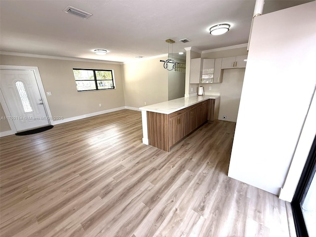 kitchen featuring visible vents, white cabinets, ornamental molding, a peninsula, and light countertops