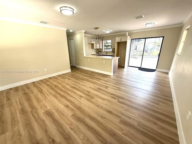 unfurnished living room with baseboards, visible vents, and ornamental molding